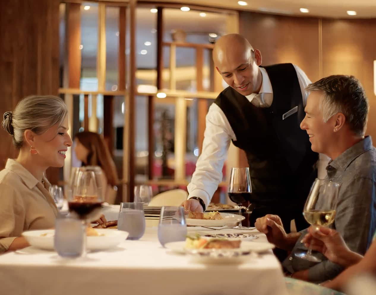 A waiter serving dinner to a couple at a table.