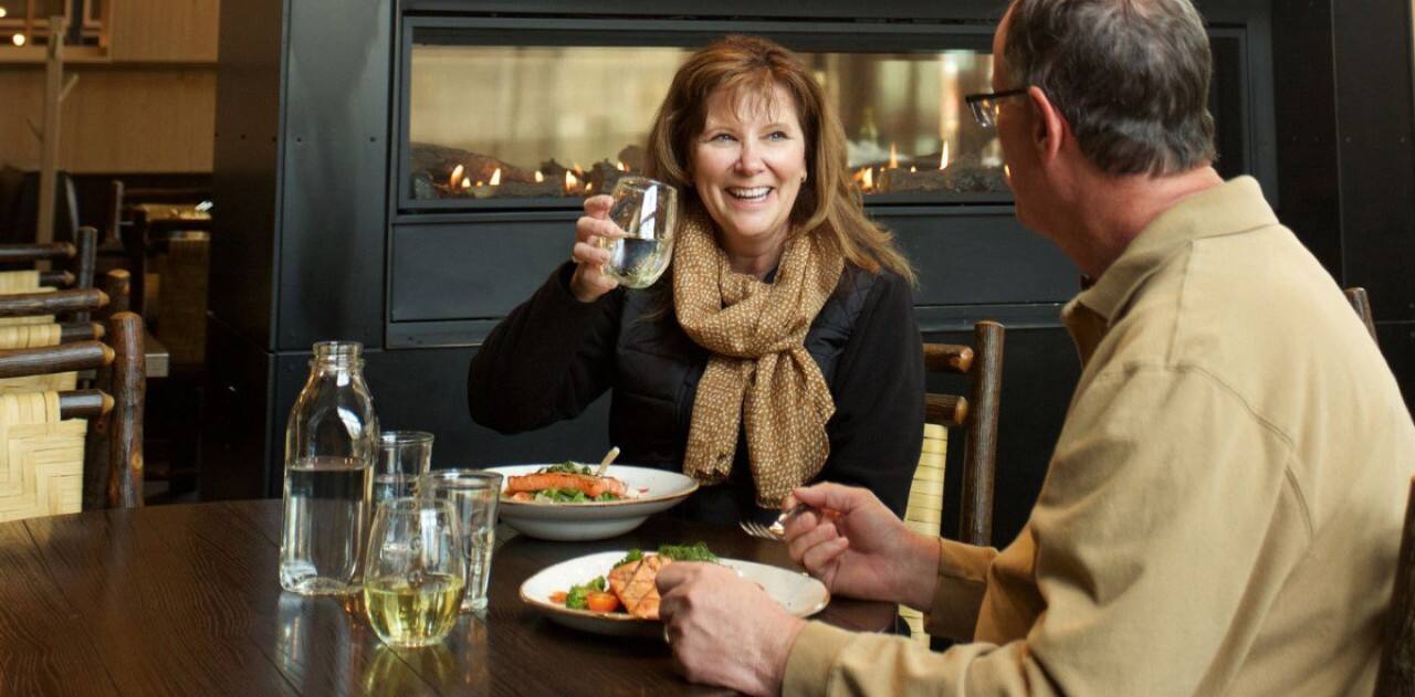 Couple enjoying a meal at an Alaska lodge during a Holland America Line land and sea Cruisetour.
